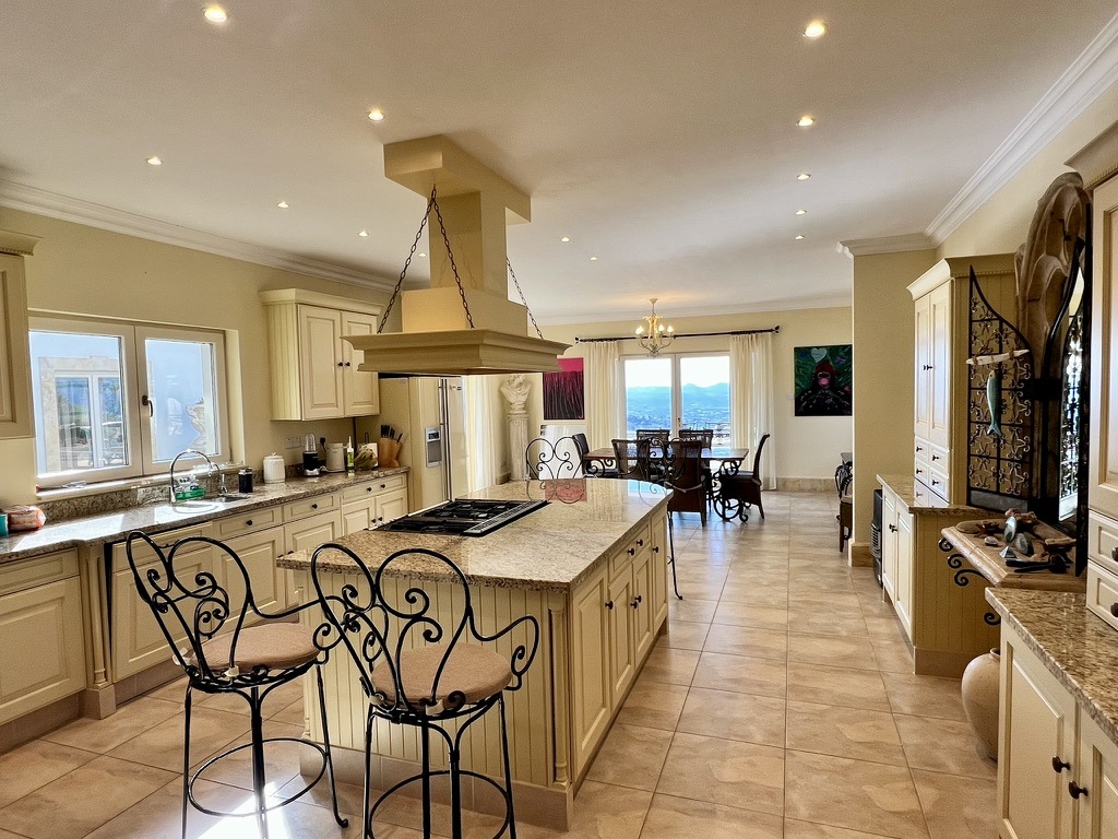 Villa Onassa’s kitchen with island seating, dining table and views through the doors