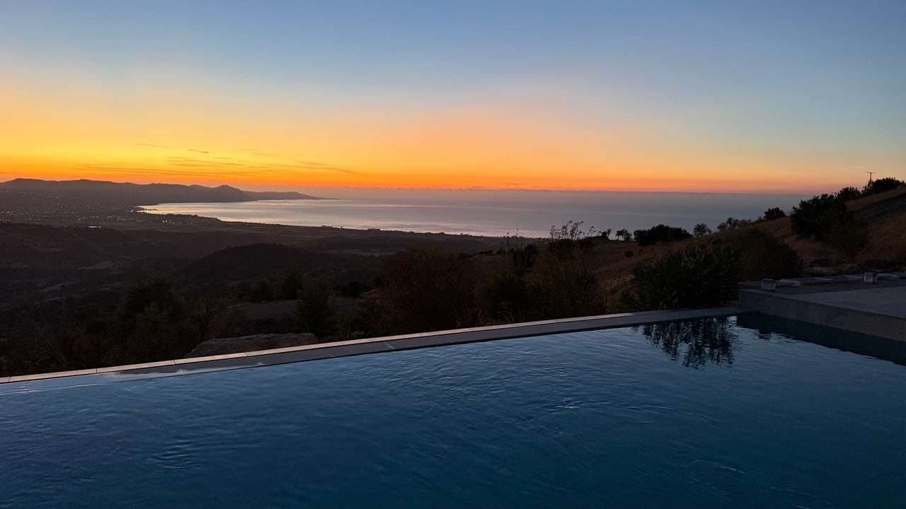 The pool at Villa Onassa overlooking the hills and sea at sunset